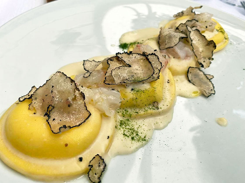 Raviolo ripieno di burrata con crudo di scampi e tartufo nero