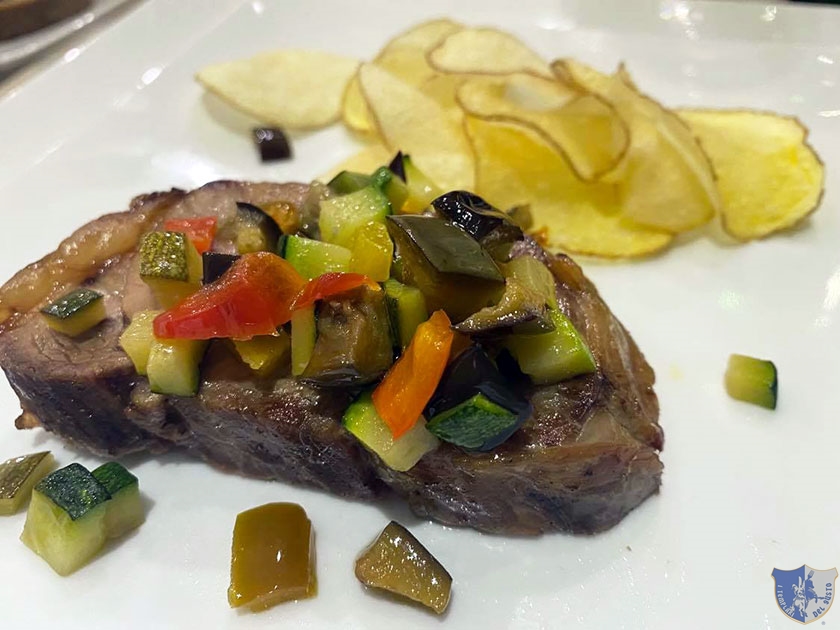 Maialino alle erbe aromatiche con chips di patate e misticanza di verdure