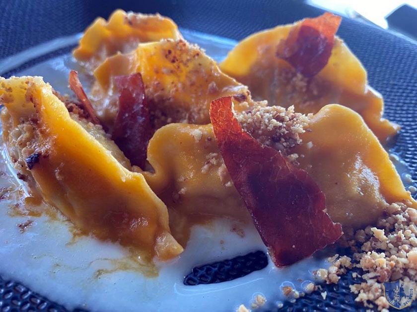 Ravioli ripieni di funghi porcini e patate con riduzione di zucca e speck croccante